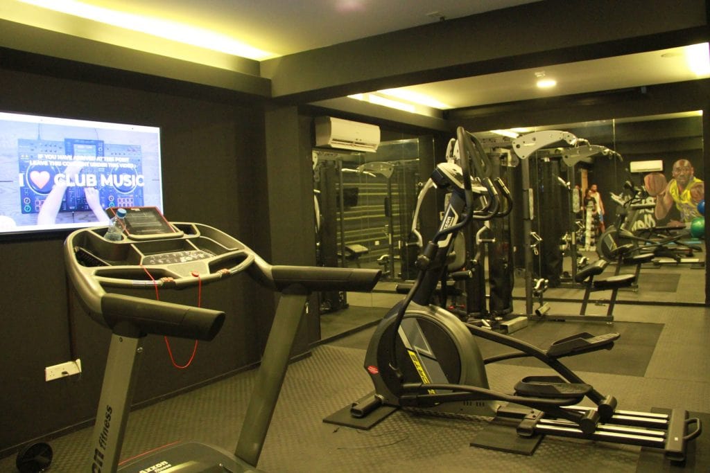 Modern cardio and strength training equipment in a gym with a large digital screen displaying a heart and the text 'CLUB MUSIC'.